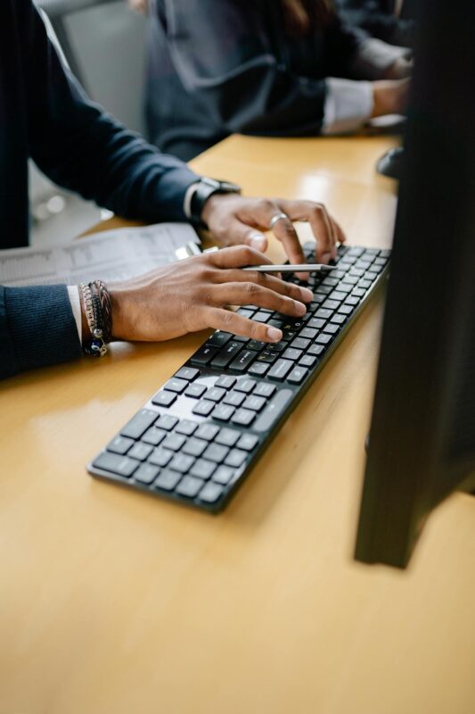 Close-up of hands typing on keyboard in an office setting, showcasing work professionalism.